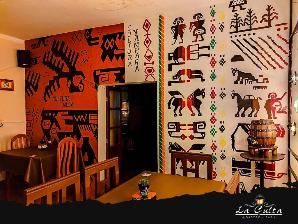 a room with a wall covered in art at La Culta hostal & centro cultural in Sucre