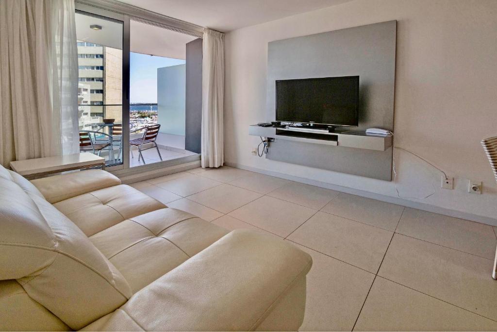 a living room with a couch and a flat screen tv at Oceana Suites en SeaPort, vista al mar in Punta del Este
