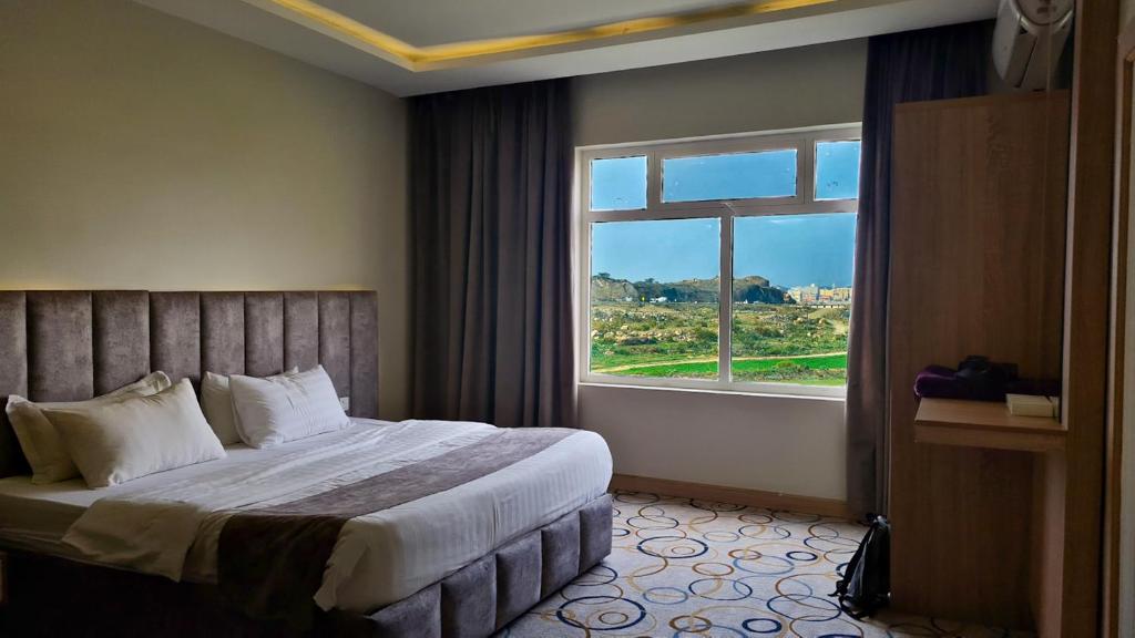 a hotel room with a bed and a large window at جولدن العرين Golden Al3areen abha hotel in Abha