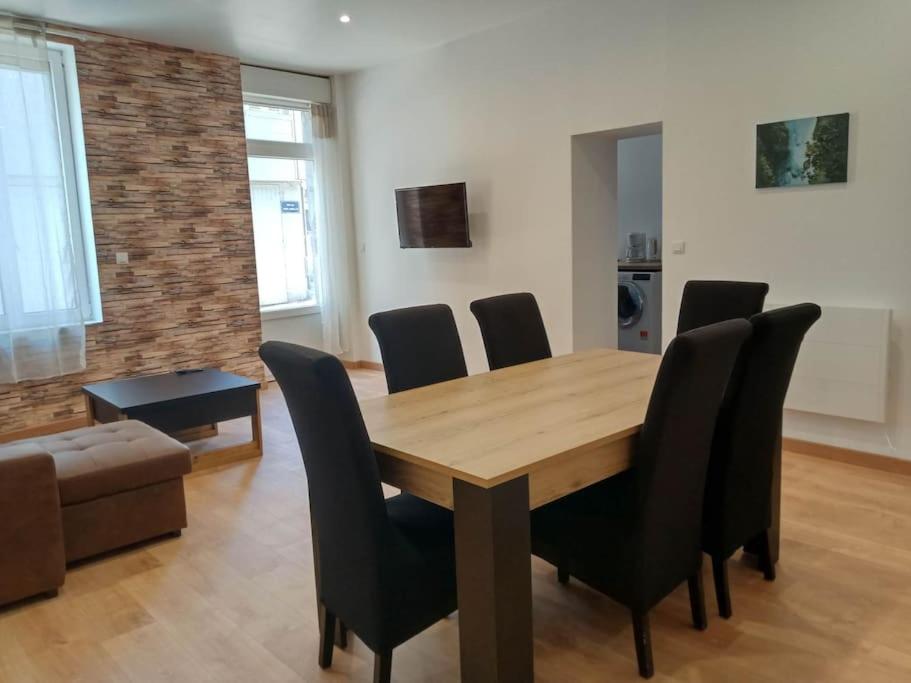 a dining room with a wooden table and black chairs at Gonnelles Appartement T3 Centre Ville RDC D in Agen