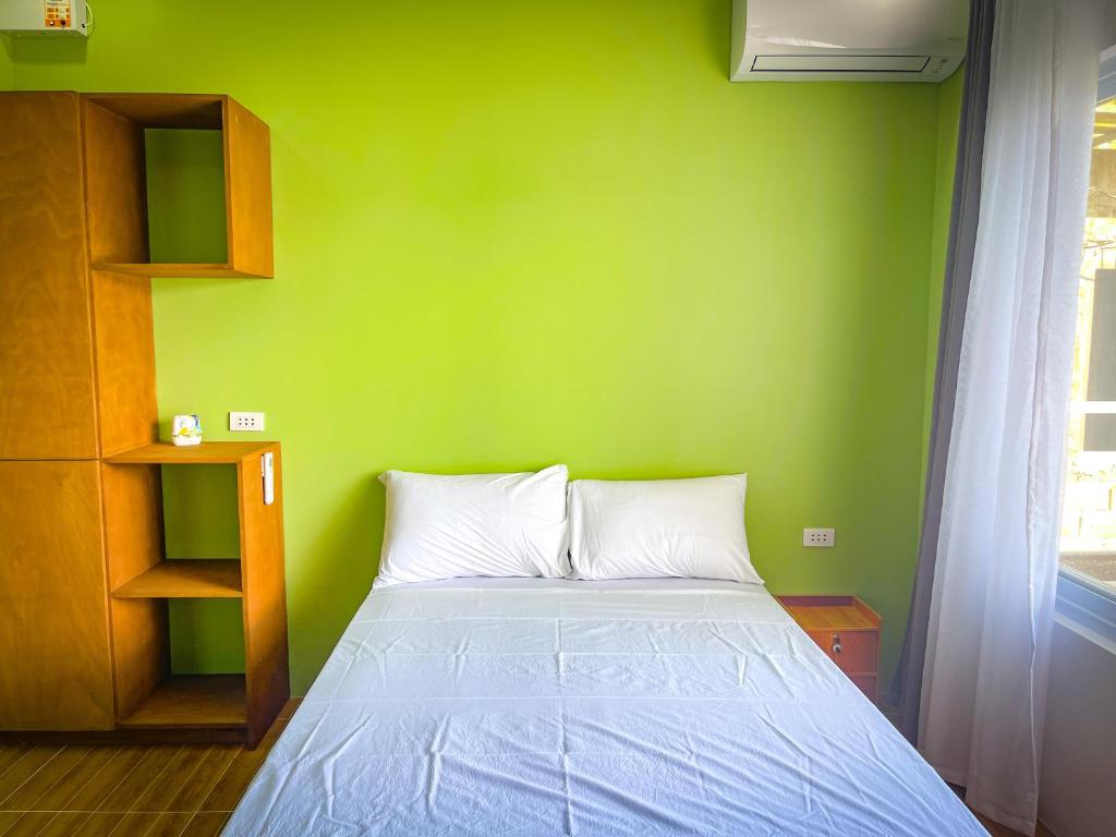 a green bedroom with a bed and a green wall at Lovely Beach House in Anilao in Mabini