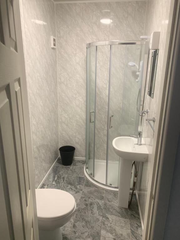 een badkamer met een douche, een toilet en een wastafel bij JEANNE in Blackpool