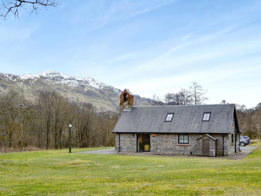 a stone house in a field with mountains in the background at Ardlui Church in Ardlui