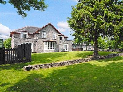 a large stone house with a tree in the yard at Cartmel Cottage in Lindale