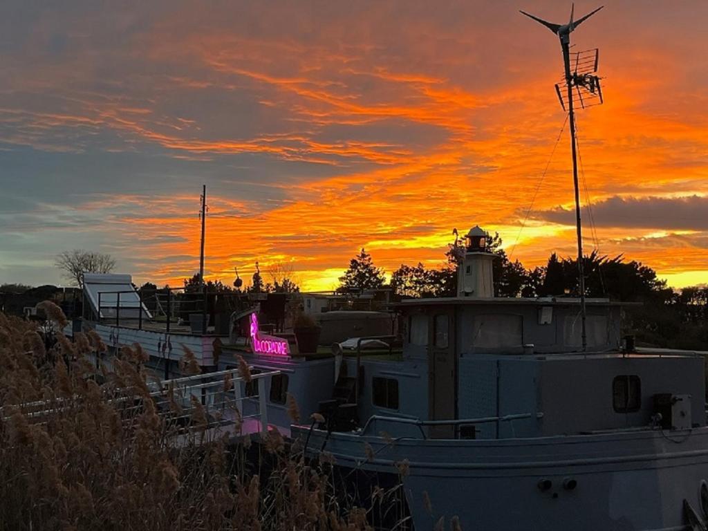 un bateau est amarré devant un coucher de soleil dans l'établissement Séjour atypique et insolite sur notre péniche La Coradine avec grand spa, à Aigues-Mortes