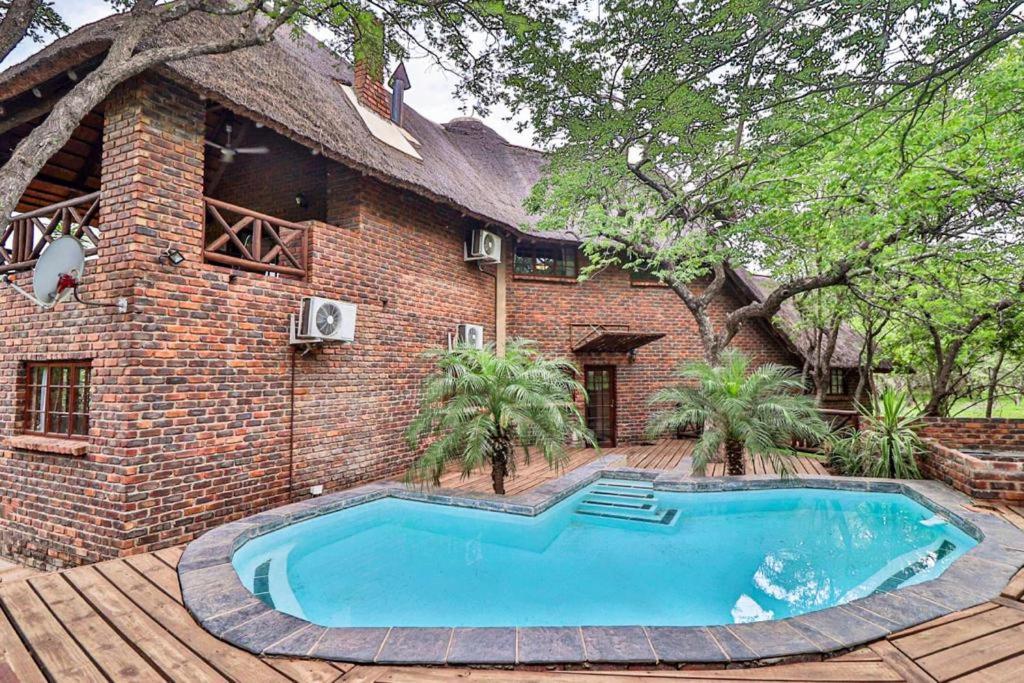 a brick house with a swimming pool in front of it at Luxury Kruger Escape in Marloth Park