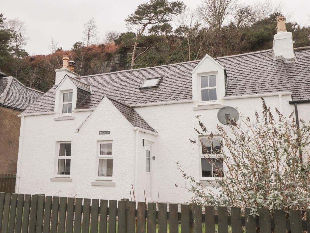 a white house with a fence in front of it at Craigard in Balmacara