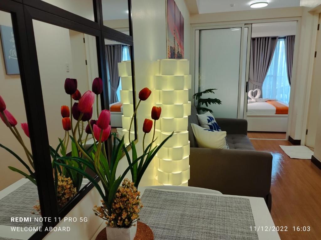 a living room with red tulips in a vase on a table at Celandine Residence by DMCI in Manila