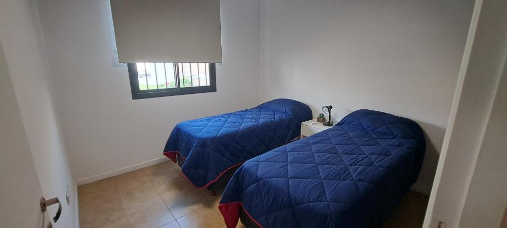Duas camas azuis num quarto com uma janela em Balcones Mendocinos em Mendoza