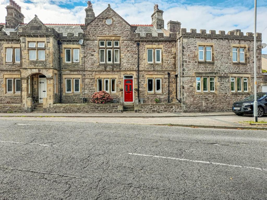 an old stone building with a red door on a street at The Haven in Heysham