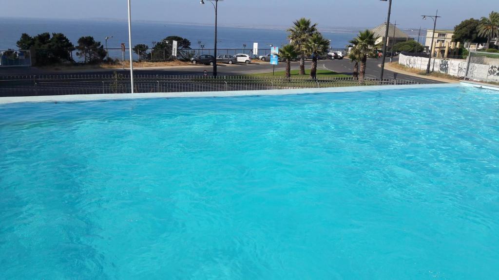 a large blue swimming pool with the ocean in the background at lindo y exclusivo Departamento en Costa Concón , con piscina vista al mar y otra temperada in Concón