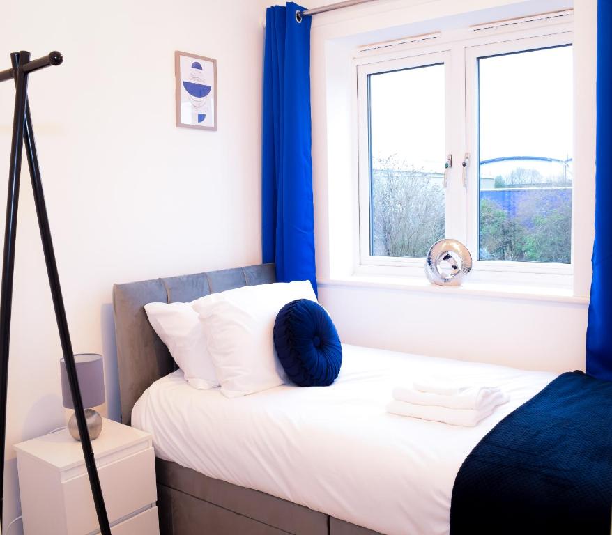 a bedroom with a bed with blue curtains and a window at Modern 3 Bed House in Wolverhampton