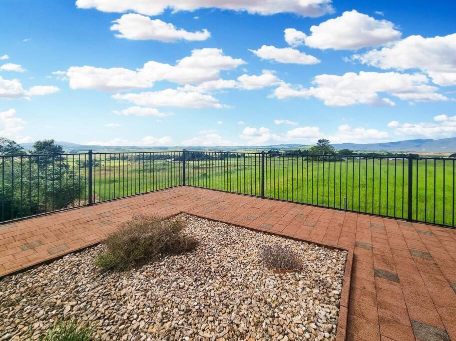 une terrasse avec une clôture noire et un champ dans l'établissement A picturesque 3 bedroom house with splendid views, à Atherton