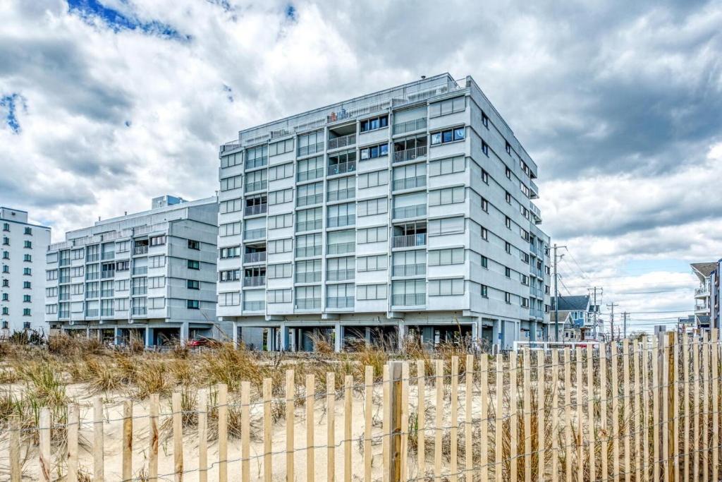 a tall building behind a fence in front of a building at Oceana II 109 condo in Ocean City