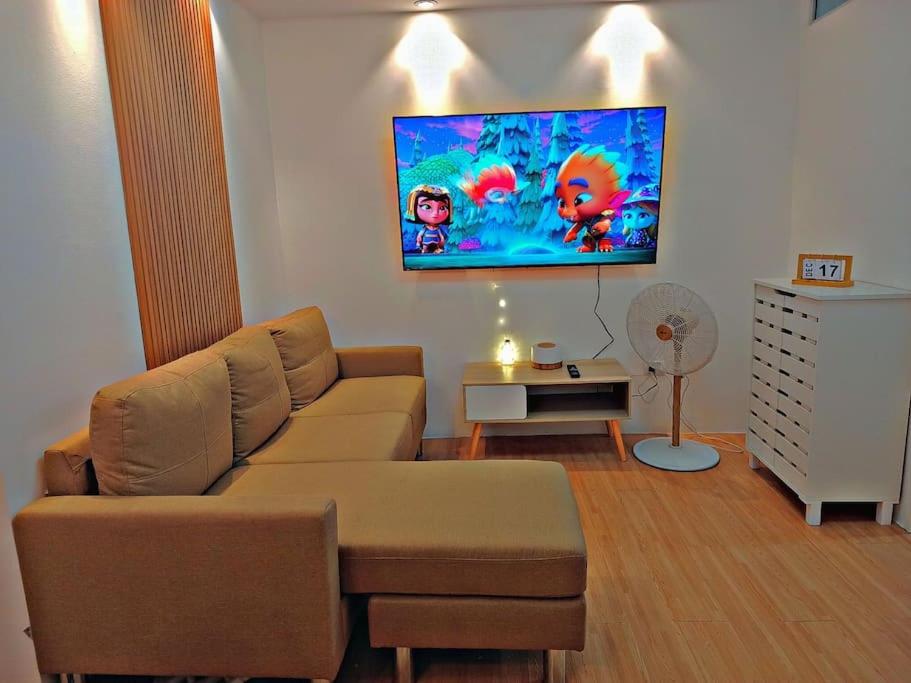 a living room with a couch and a tv on the wall at Minamalist Condo Staycation in Imus