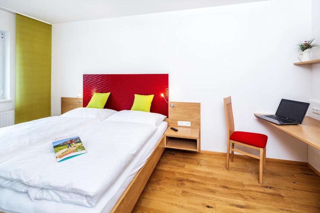 a bedroom with a bed with a red headboard and a red chair at Gasthaus-Pension Sandner Linde in Steinbach an der Steyr