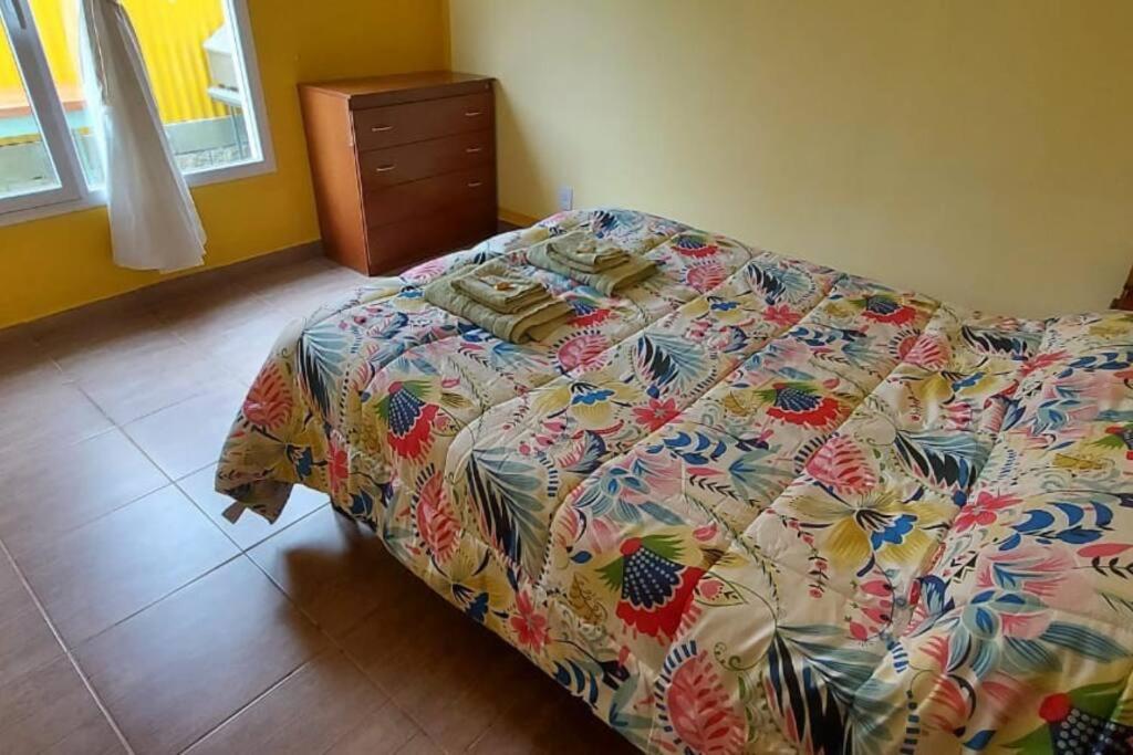 1 dormitorio con 1 cama con un edredón colorido en Departamentos Ensueños en Río Gallegos
