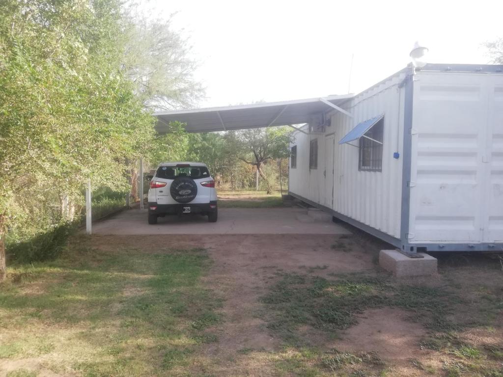 a car parked under a building next to a trailer at container in San Gerónimo