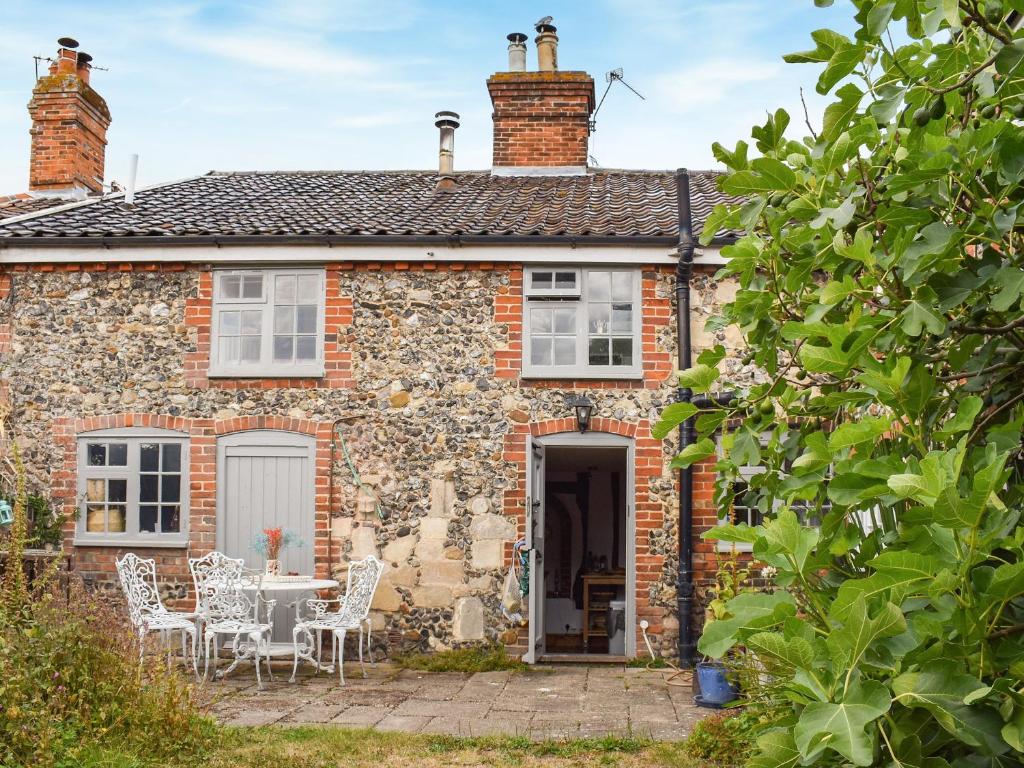 a stone cottage with a table and chairs in front of it at Ivy Cottage in Metfield