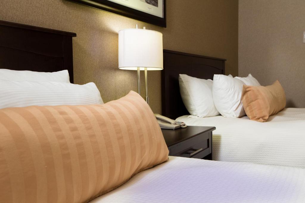 a hotel room with two beds and a lamp on a table at The Kanata Fort Saskatchewan in Fort Saskatchewan