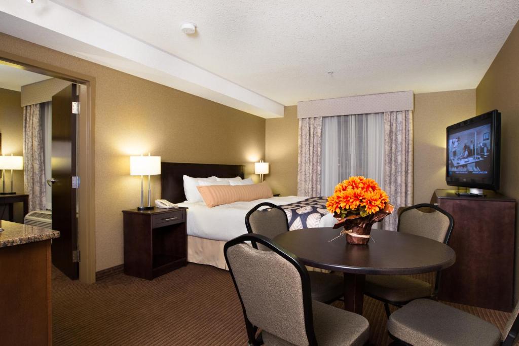 a hotel room with a bed and a table with flowers on it at The Kanata Fort Saskatchewan in Fort Saskatchewan