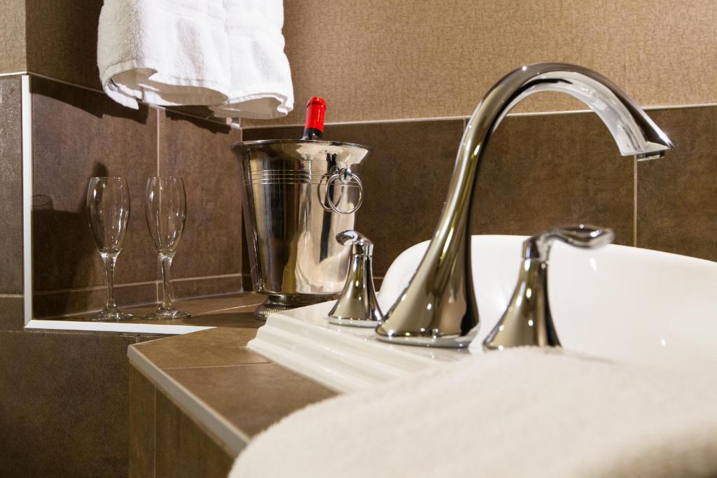 a bathroom sink with a faucet and two wine glasses at The Kanata Fort Saskatchewan in Fort Saskatchewan