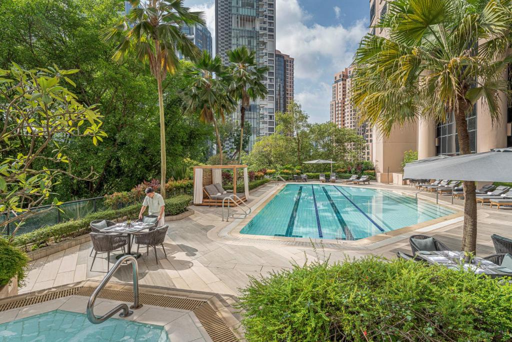 uma pessoa sentada numa mesa ao lado de uma piscina em Four Seasons Hotel Singapore em Singapura