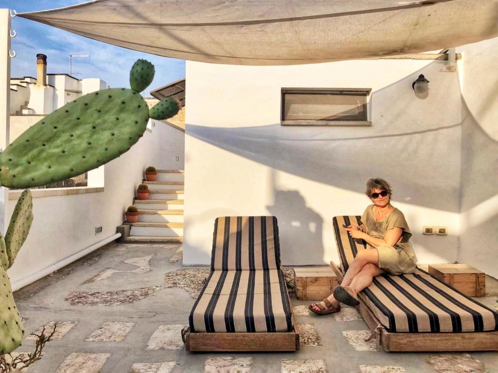 eine Frau, die auf einem Stuhl auf einer Terrasse sitzt in der Unterkunft Cà Mì Apartment in Galatone
