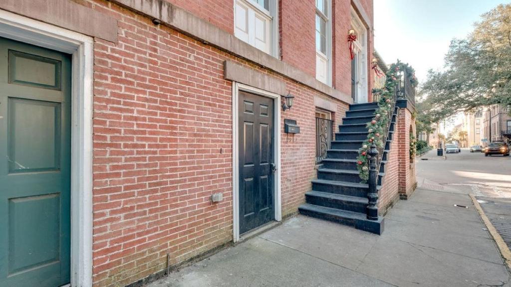 a brick building with a door and stairs next to a street at 4 Bedroom Beauty Steps from the River in Savannah