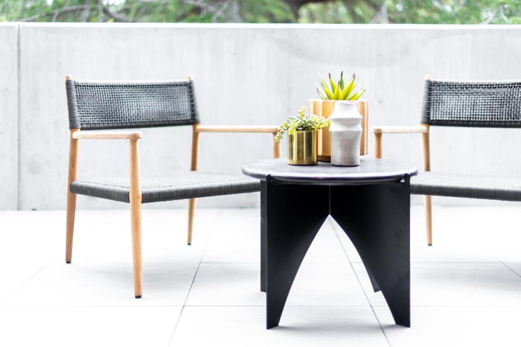 two chairs and a table with plants on a patio at And Apartments in Canberra