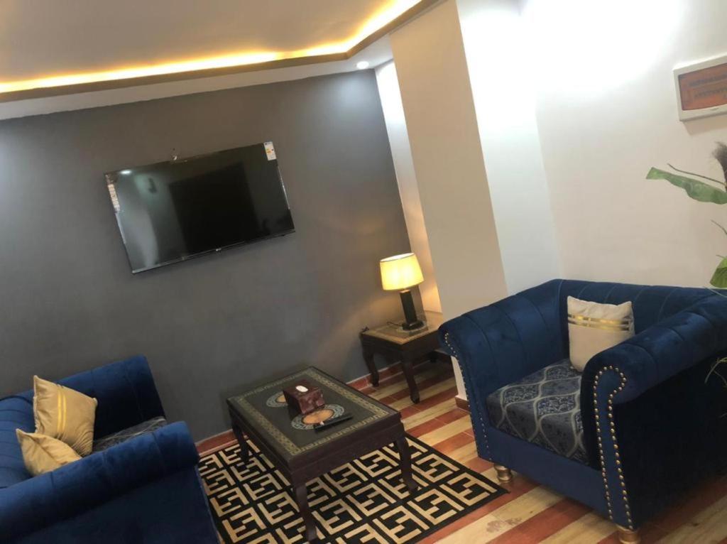 a living room with two blue couches and a flat screen tv at Lux Aparts Jhelum in Jhelum