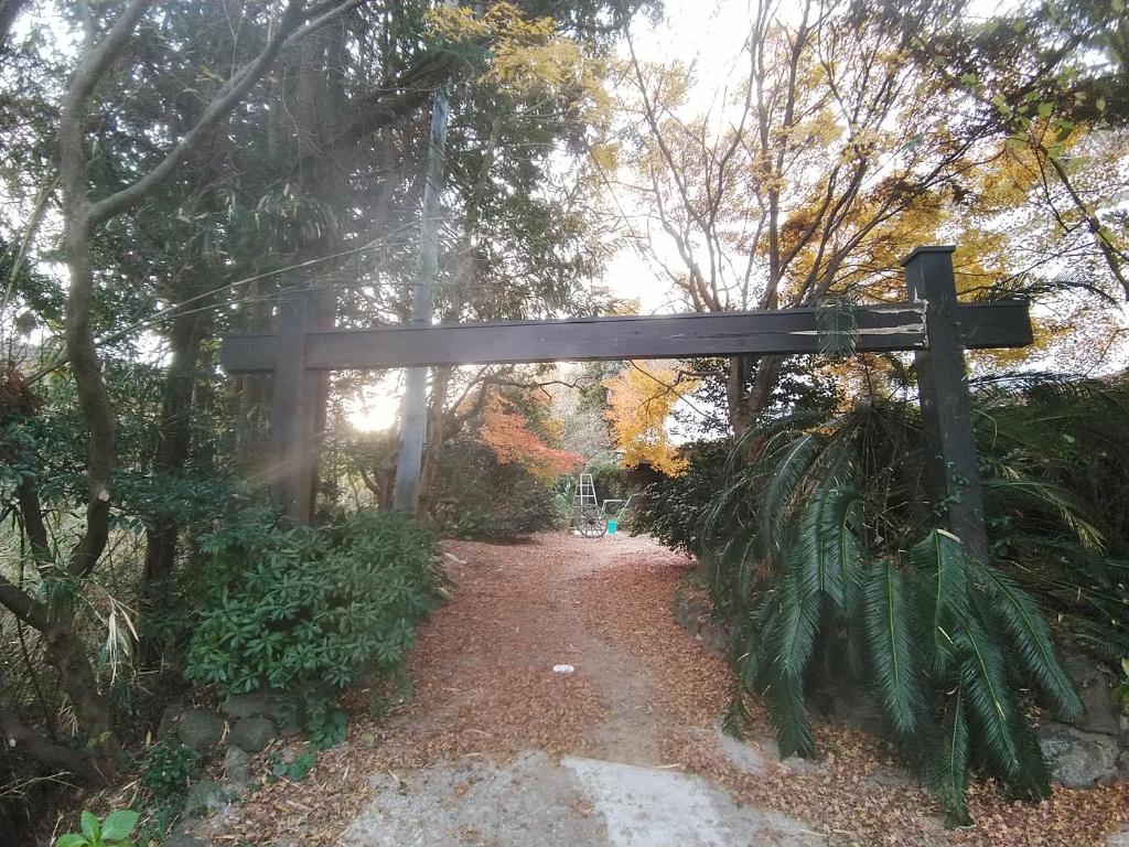 una puerta de madera en un camino en un bosque en 横城ゲストハウス, en Kitsuki