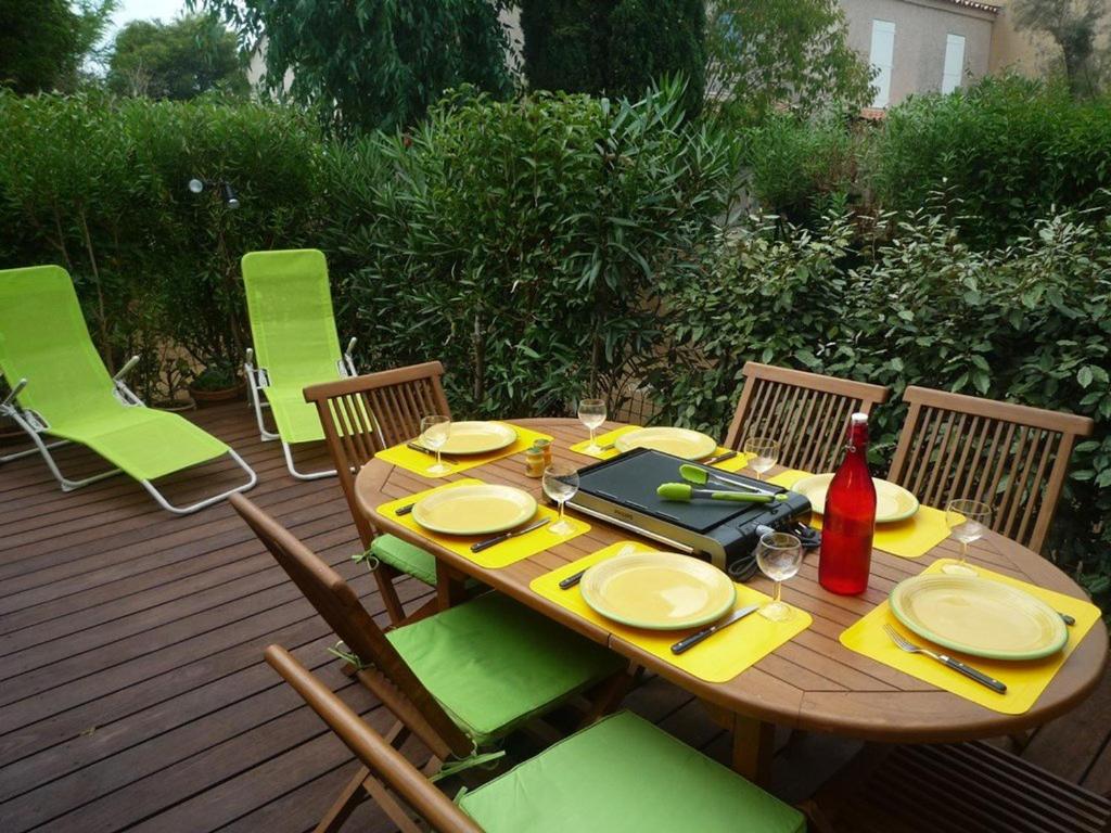 - une table et des chaises en bois sur une terrasse avec une table et une bouteille dans l'établissement Maison Le Lavandou, 2 pièces, 6 personnes - FR-1-251-156, au Lavandou