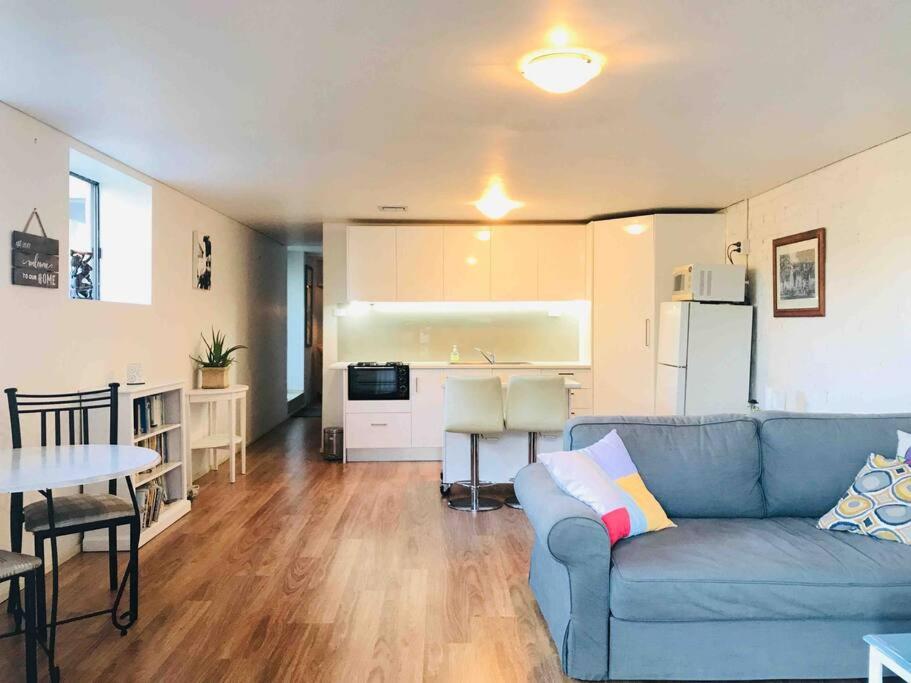 a living room with a blue couch and a kitchen at Beach to Bush in Stanwell Park