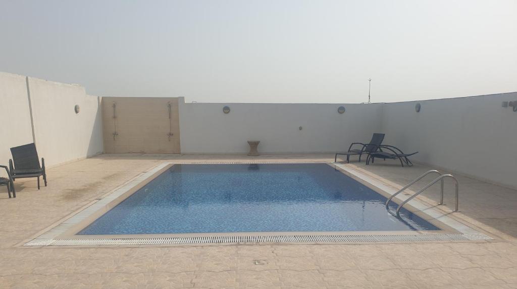a large swimming pool in a room with chairs at 1-Berdroom Apartment Rental Unit With Pool in Dubai Land Residence Complex in Dubai