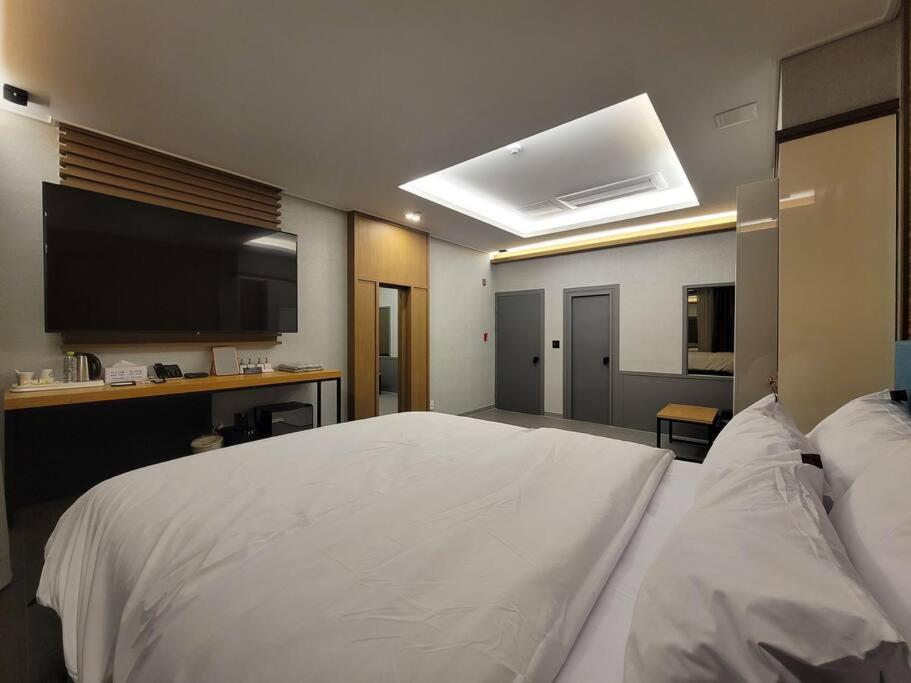 a bedroom with a large white bed and a desk at Bigbell House in Namyangju