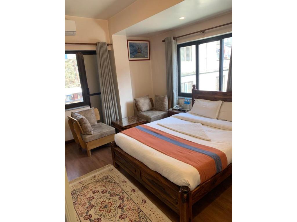 Hotel Ramanam في كاتماندو: غرفة نوم بسرير وكرسي ونافذة