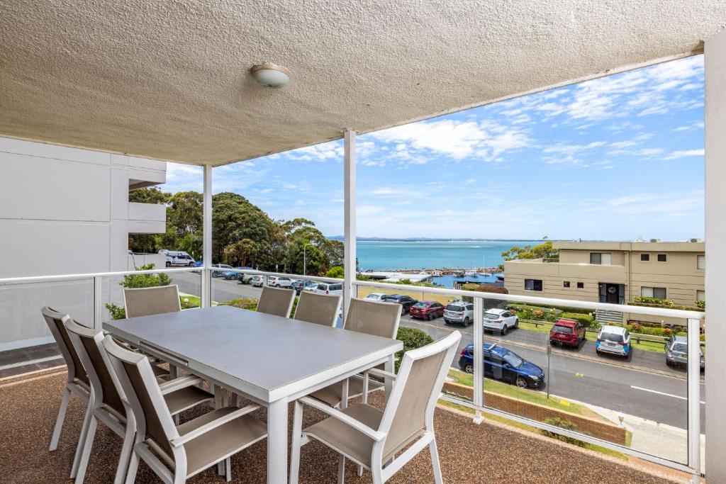 a table and chairs on a balcony with a view of a street at Birdseye View Apartment at Nelson Bay in Nelson Bay