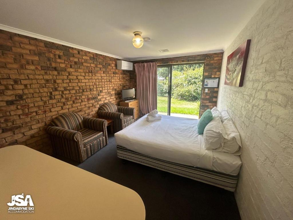 a hotel room with a bed and a brick wall at Ellswood 1 in Jindabyne