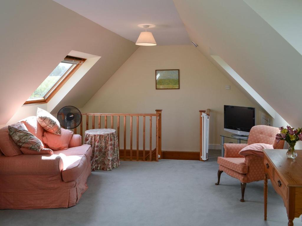 a living room with a couch and a tv at Broad Cottage Boathouse in Ranworth