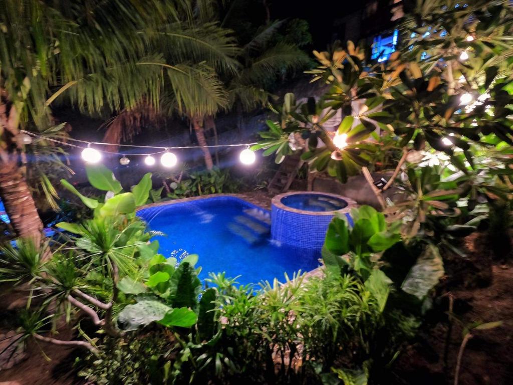 a swimming pool in a garden with trees and lights at Tanaw sa Anilao in Mabini