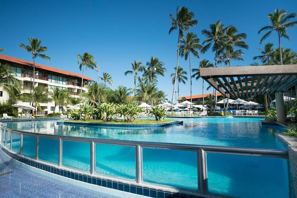 a swimming pool at a resort with palm trees at Marulhos Resort Beach - 2 quartos & 1 quarto in Porto De Galinhas