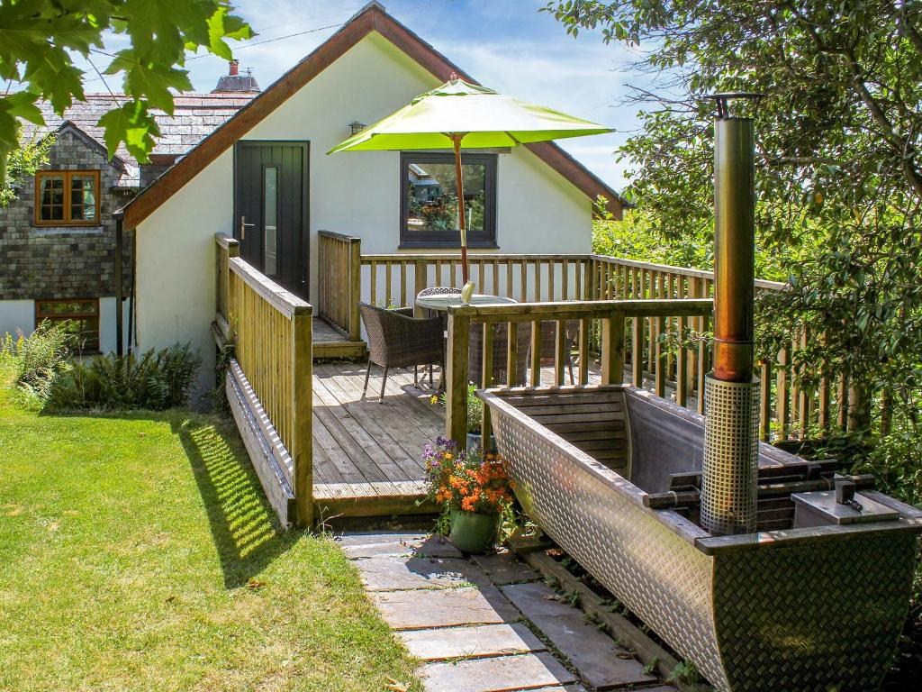 a wooden deck with a table and an umbrella at Little Fursdon Apartment in Merrymeet