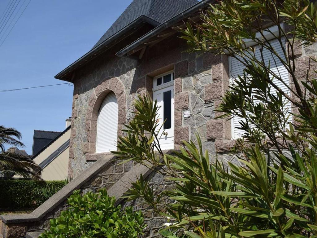 une maison en pierre avec une porte blanche et une fenêtre dans l'établissement Maison en pierre 3* rénovée, jardin, WIFI, proche plage et commerces, Ploumanac'h - FR-1-368-87, à Perros-Guirec