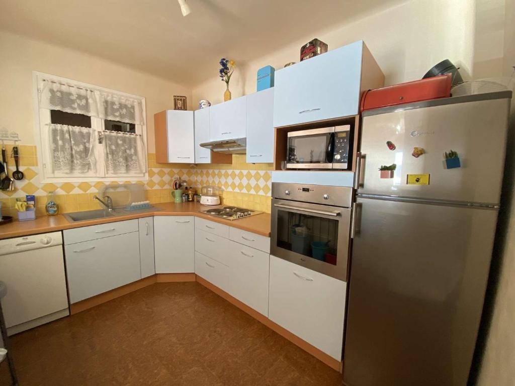 a kitchen with white cabinets and a stainless steel refrigerator at Appartement Casaglione-Tiuccia, 2 pièces, 4 personnes - FR-1-61-477 in Casaglione