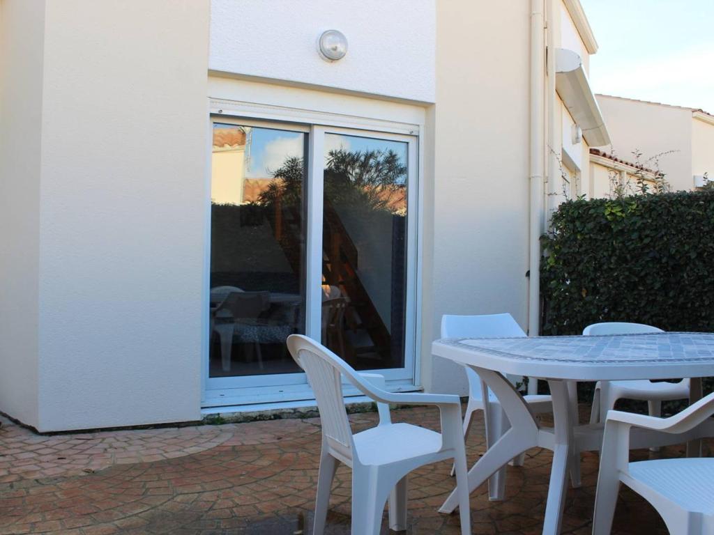 patio ze stołem i krzesłami oraz oknem w obiekcie Charmante maison avec piscine, 6 couchages, proche plage - Saint-Denis-d’Oléron - FR-1-246A-154 w mieście Saint-Denis-dʼOléron