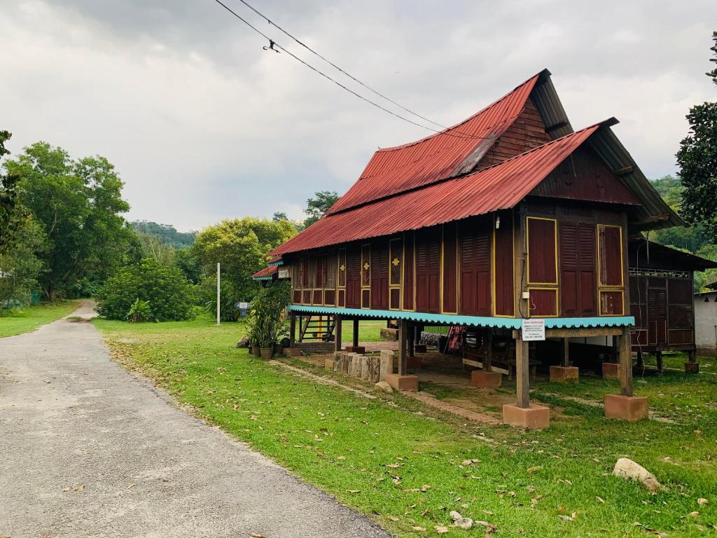 uma pequena casa de madeira com um telhado vermelho em Port Mancing Fishing Village em Kampong Ulu Kalong