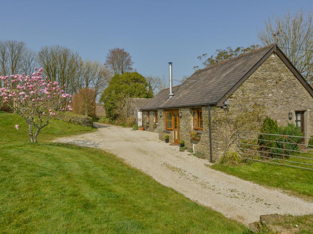 a stone house on a dirt road next to a field at Hook Cottage in Looe