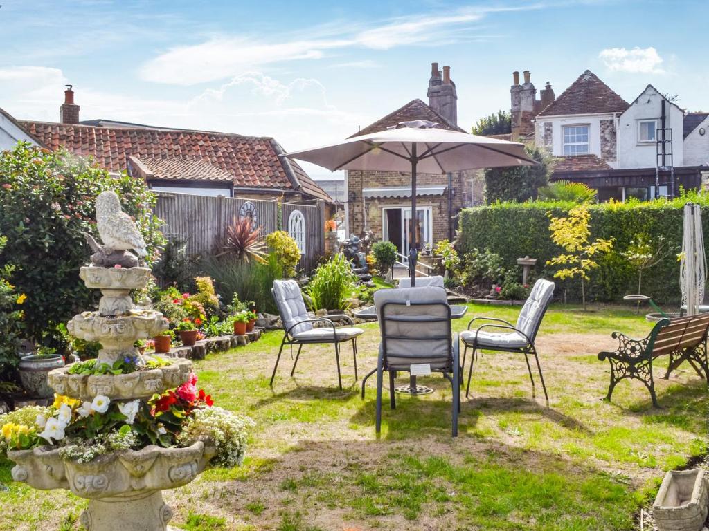 um jardim com uma mesa e cadeiras e um guarda-sol em Queensland Cottage em St Margarets at Cliff