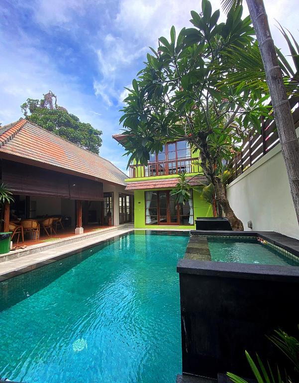 a swimming pool in front of a building with trees at Villa Mudha 3 Sanur in Sanur
